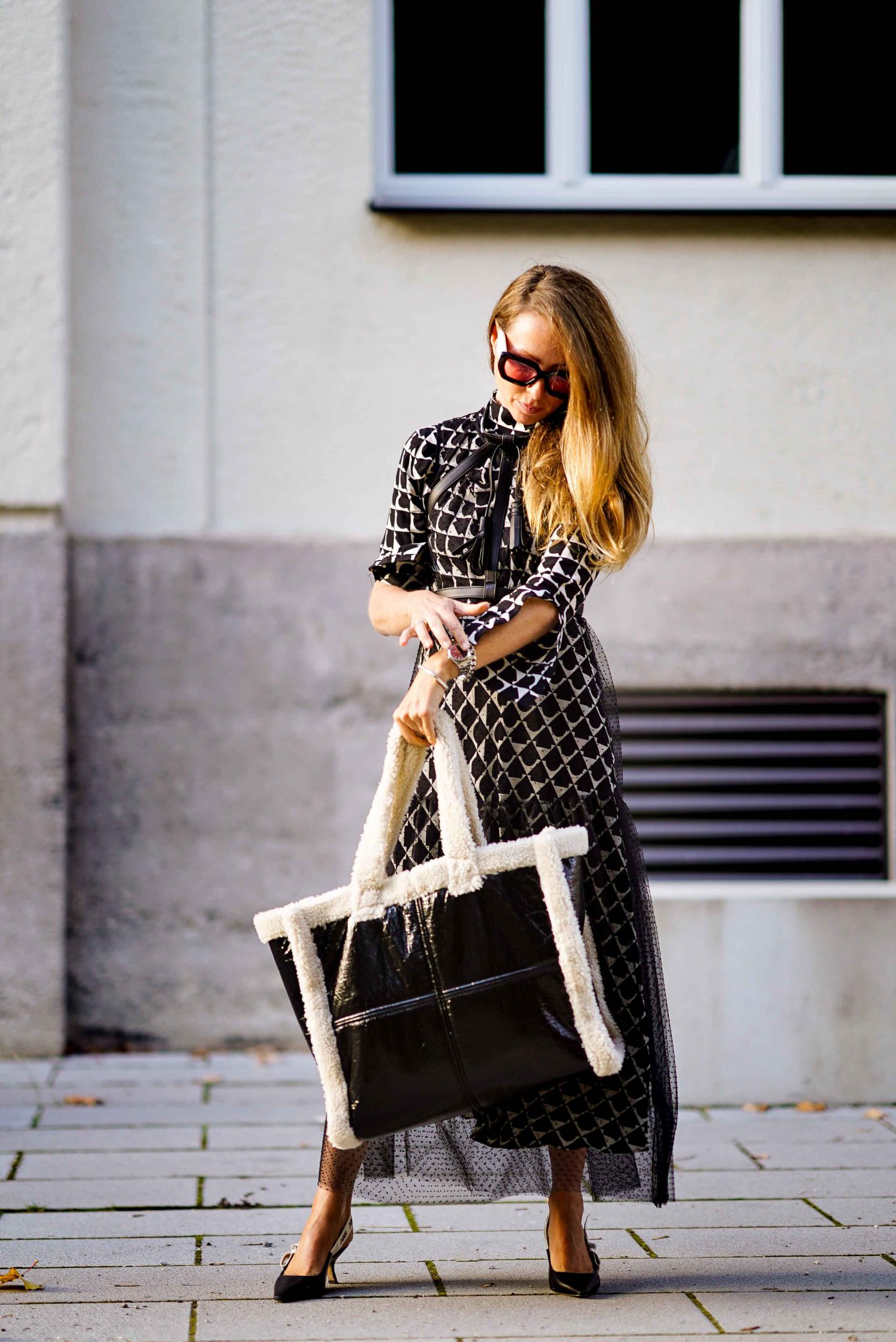 Fashion Bloggerin Nicki Nowicki mit dem Taschen Trend der Saison: Stand Studio Bag aus schwarzem Lack und Fake Fur